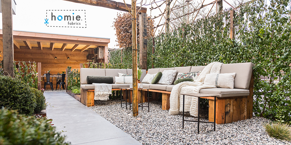 Buitenlounge met Homie Fabrics kussens in een groene tuin